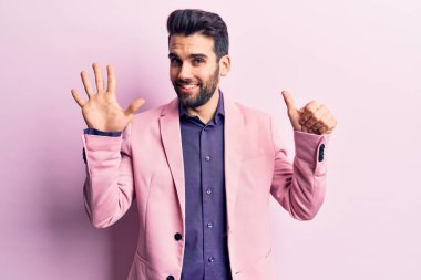 Sakallı, zarif ceketli, altı numaralı parmaklarıyla gösteriş yapan, kendinden emin ve mutlu gülümseyen genç yakışıklı adam.. 