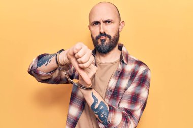 Kızgın yüzlü, mahkum kelepçesi takan genç yakışıklı bir adam. Negatif işaretler, baş parmakları aşağıda, reddedilme kavramı. 