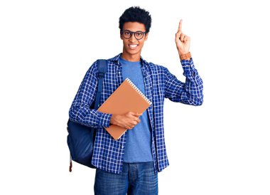 Afrika kökenli Amerikalı genç bir adam sırt çantası takıyor. Elinde kitap var. Şaşırmış, şaşırmış ve parmaklarıyla işaret ediyor ve kollarını kaldırıyor.. 