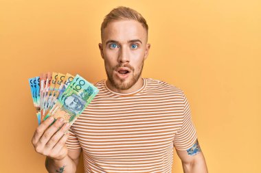 Avustralya Doları 'nı elinde tutan genç, beyaz bir adam ağzı açık kalmış, korkmuş ve hayrete düşmüş. 