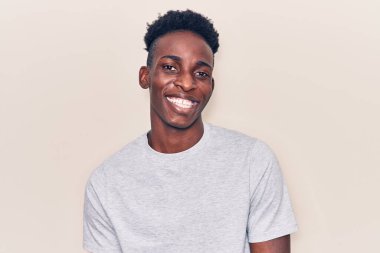 Genç Afro-Amerikalı sıradan kıyafetler giymiş, kameraya seksi bir ifadeyle bakıyor, neşeli ve mutlu bir yüzle.. 