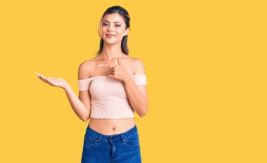 Gündelik giysiler giyen genç ve güzel bir kadın kameraya hayret ediyor ve gülümsüyor.. 