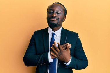 Yakışıklı, takım elbiseli, kravatlı, göğsünde elleri göğsünde gülümseyen, yüzünde minnet ifadesi olan genç bir adam. sağlık kavramı. 