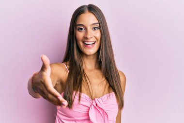 Kolsuz tişörtlü, sıradan giyinen genç İspanyol kadın selamlaşma ve dostça bir şekilde tokalaşıyor. başarılı iş. 