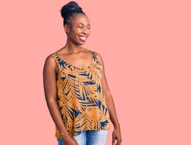 Genç Afro-Amerikan kadın, günlük giysiler içinde kameraya seksi bir ifadeyle bakıyor, neşeli ve mutlu bir yüzle.. 