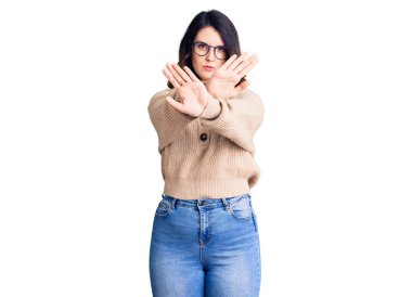 Güzel, genç, esmer bir kadın. Günlük kıyafetler ve gözlük takıyor. Reddedilme ifadesi. 