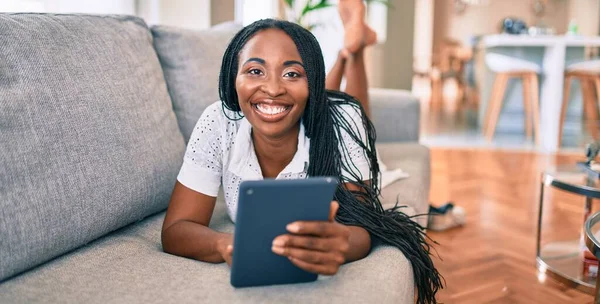 Joven Mujer Afroamericana Sonriendo Feliz Usando Tableta Puesta Sofá Casa —  Fotos de Stock