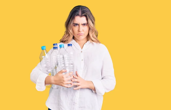 Junge Kaukasierin Mit Recycling Plastikflaschen Nachdenklicher Haltung Und Nüchternem Gesichtsausdruck — Stockfoto