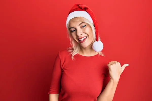 Молода Блондинка Різдвяному Капелюсі Посміхається Щасливим Обличчям Дивлячись Вказуючи Бік — стокове фото
