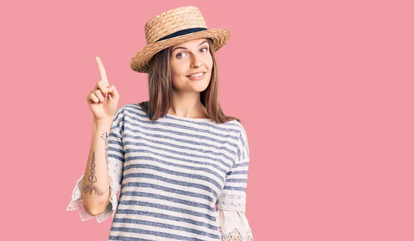 自信と幸せ笑顔ながら夏の帽子をかぶった美しい白人女性が現れ 指のナンバー1で指摘します — ストック写真