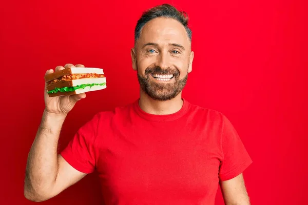 Bonito Homem Meia Idade Comendo Sanduíche Olhando Positivo Feliz Sorrindo — Fotografia de Stock