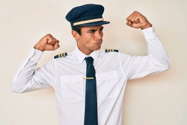 Young Hispanic Man Wearing Airplane Pilot Uniform Showing Arms Muscles — Stock Photo, Image