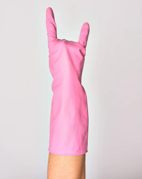 戴着粉色清洁手套的高加索年轻女子的手 手指头上有角形标志 在孤立的白色背景上做岩石符号 — 图库照片