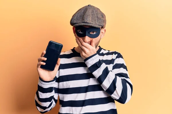 Young Handsome Bald Man Wearing Burglar Mask Holding Smartphone Covering — Stock Photo, Image