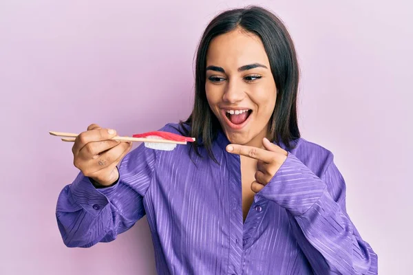 Joven Morena Comiendo Sushi Usando Palillos Sonriendo Feliz Señalando Con —  Fotos de Stock