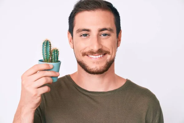 Ung Stilig Man Håller Liten Kaktus Potten Ser Positiv Och — Stockfoto