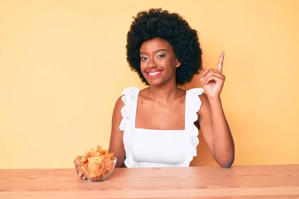 Jong Afrikaans Amerikaans Vrouw Houden Nachos Chips Glimlachen Gelukkig Wijzend — Stockfoto