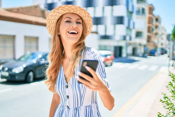 아름다운 금발의 모자를 행복하게 있습니다 도시의 거리에서 스마트폰으로 웃으며 — 스톡 사진
