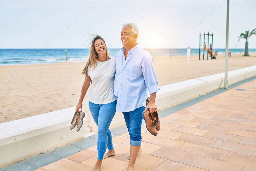 Middle age hispanic couple smiling happy and hugging walking at the promenade