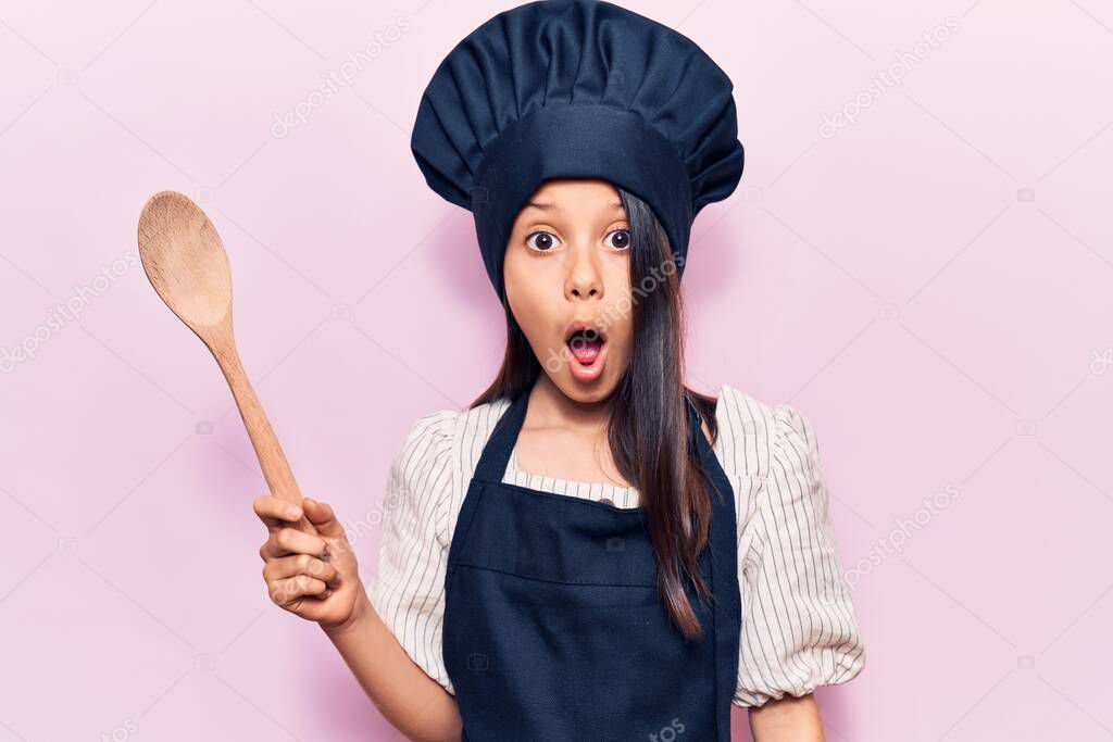 Beautiful child girl wearing cooker uniform scared and amazed with open mouth for surprise, disbelief face 