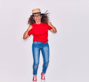 Orta yaşlı, güzel İspanyol bir kadın, sıradan kıyafetler giyiyor ve mutlu bir şekilde gülümsüyor. Beyaz arka planda gülümseyerek atlamak