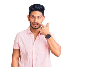 Yakışıklı Latin Amerikalı sıradan bir yaz tişörtü giyen, el parmağı ve burnu olan, neşeli gülümseyen bir genç. güzellik konsepti 