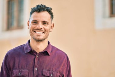 Genç İspanyol adam gülümseyerek şehirde mutlu mesut dikiliyor..