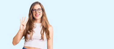 Güzel, beyaz, günlük kıyafetler ve gözlük takan genç bir kadın dört numarayı gösterip işaret ederken kendinden emin ve mutlu bir şekilde gülümsüyor.. 