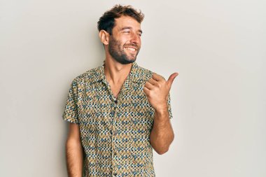 Sakallı, sıradan moda tişörtlü yakışıklı başparmağını kaldırmış, ağzı açık gülümsüyor. 