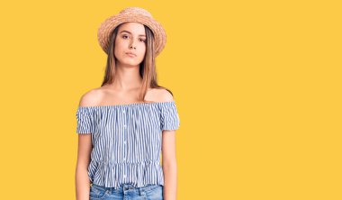 Şapka ve tişört giyen genç ve güzel bir kız. Yüzünde ciddi bir ifadeyle rahatlamış. Basit ve doğal bir şekilde kameraya bakıyorsun.. 