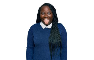 Saçları örgülü, sıradan kıyafetler giyen, dilini dışarı çıkaran, komik bir ifadeyle mutlu genç siyahi kadın. duygu kavramı. 