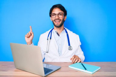 Yakışıklı İspanyol üniformalı doktor klinikte çalışıyor. Bir fikir veya soruyla gülümsüyor ve mutlu bir yüzle işaret ediyor. 