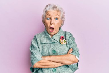 Kıdemli gri saçlı kadın, günlük kıyafetler giyiyor. Şaşırmış ve şaşırmış bir halde, şaşkınlık ve şaşkınlık dolu bir ifade, korku ve heyecanlı bir yüz.. 