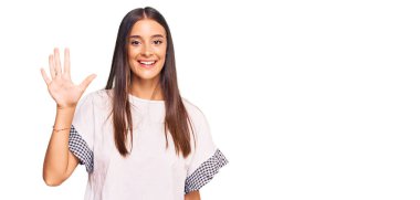 Genç İspanyol kadın gündelik kıyafetler giyer ve beş numarayı göstererek gülümserken kendinden emin ve mutluydu.. 