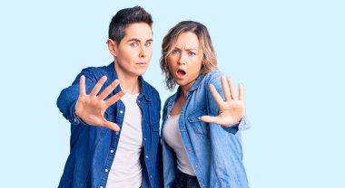 Sıradan kıyafetler giyen bir çift kadın avuç içi hareketlerini durduruyor, kızgın ve hayal kırıklığına uğramış bir ifade takınıyor. 