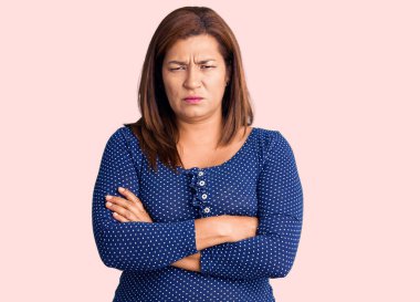 Normal giyinen orta yaşlı güzel bir kadın soyutlanmış pembe arka planda duruyor. Depresyon sorunlarından sıkılmış ve yorgun görünüyor.