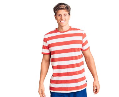 Yüzünde mutlu ve havalı bir gülümseme olan sıradan kıyafetler giyen genç yakışıklı bir adam. şanslı kişi. 