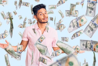 Yakışıklı Latin Amerikalı genç adam rahat bir yaz gömleği giyiyor gülümseyerek avuçlarını açıyor, sunuyor ve reklam karşılaştırması yapıyor ve dengeyi sağlıyor.