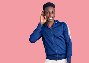 Genç Afro-Amerikan erkek spor kıyafetleri giyiyor. Kulaktan kulağa gülümsüyor. Dedikoduları ve dedikoduları dinliyor. Sağırlık kavramı. 