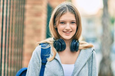 Şehre kulaklık takıp gülümseyen güzel beyaz öğrenci..