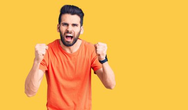 Genç, sakallı, rahat tişörtlü, sinirli, kızgın ve öfkeli bir adam öfkeyle bağırırken sinirli yumruklar sallıyor. öfke ve agresif konsept. 