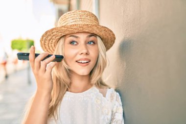 Kafkasyalı genç turist kız şehrin caddesinde akıllı telefon kullanarak sesli mesaj dinliyor..