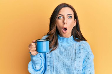 Genç esmer kadın elinde bir fincan kahve tutuyor. Korkmuş ve ağzı açık kalmış, şaşırmış, inançsız bir yüz. 