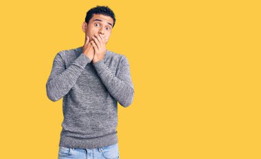 Gündelik kazak giyen İspanyol yakışıklı genç adam yanlışlıkla elleriyle ağzını kapatırken şok oldu. gizli kavram. 