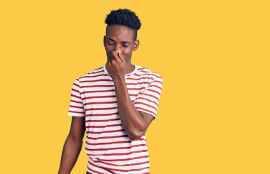 Genç, Afro-Amerikan bir adam günlük giysiler giymiş pis ve iğrenç bir koku alıyor, dayanılmaz bir koku, parmakları burnunda nefesini tutuyor. Kötü kokuyor. 