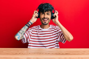 Masanın üzerinde oturan genç İspanyol adam kameraya seksi bir ifadeyle bakıyor, neşeli ve mutlu bir yüzle.. 