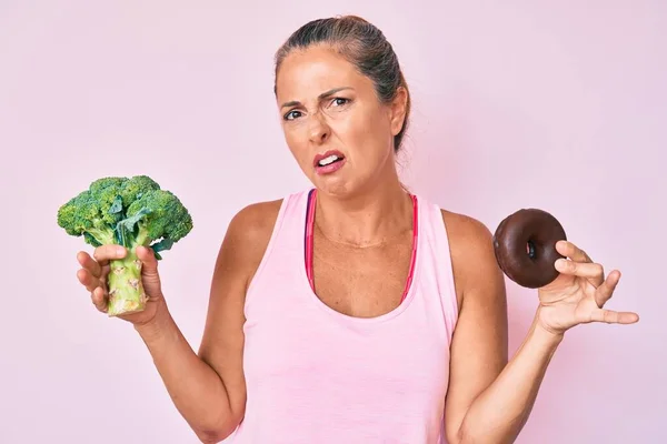 Donna Ispanica Mezza Età Con Broccoli Ciambelle Cioccolato Espressione Indiscussa — Foto Stock