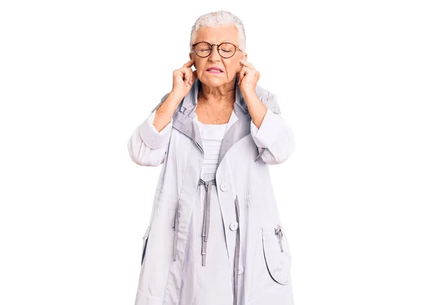 青い目と灰色の髪をしたシニア美女がカジュアルな服を着て 指で耳を覆う眼鏡をかけて 大きな音楽の音にいらいらする表情 聴覚障害の概念 — ストック写真