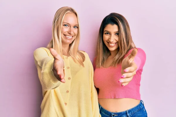 Twee Vrienden Staan Samen Roze Achtergrond Glimlachend Vriendelijk Aanbieden Van — Stockfoto