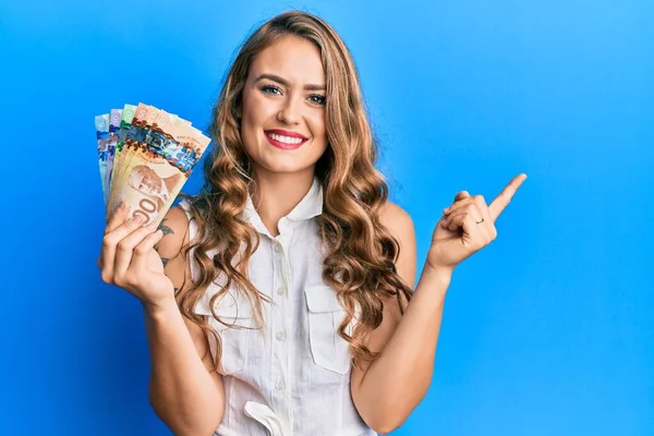 Jovem Loira Segurando Dólares Canadenses Sorrindo Feliz Apontando Com Mão — Fotografia de Stock